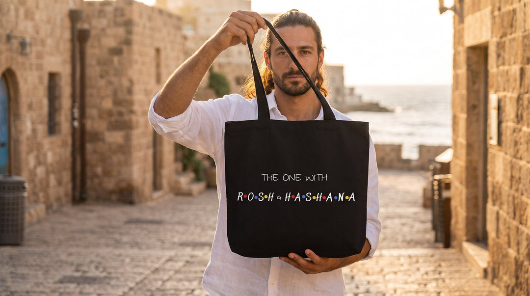 Man holding the black The One With Rosh Hashana Jewish tote bag in the old city of Jaffa