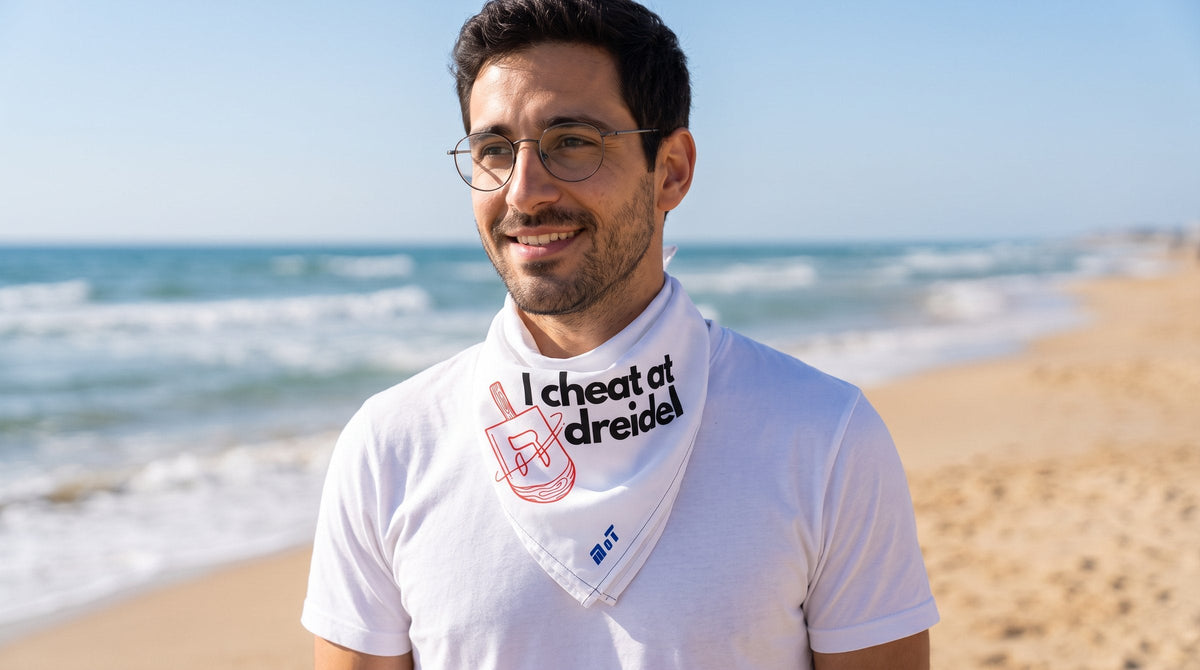 Man wearing the I Cheat At Dreidel bandana on the beach - emohtee face masks and bandanas
