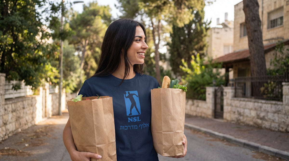 Curb Champ אלוף מדרכות T-shirt worn by a woman in a leafy residential street in Jerusalem – MoT Member of the Tribe