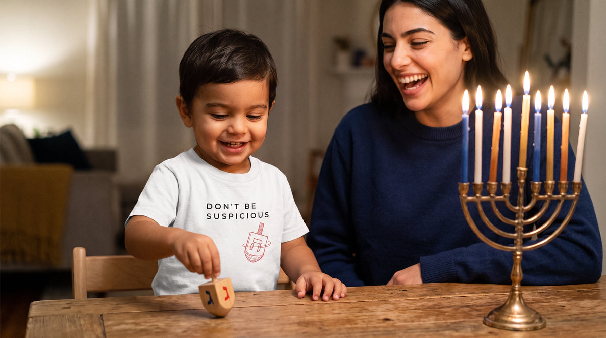 Toddler in the Don't Be Suspicious dreidel tee with a lit hanukkiah - emohtee Hanukkah shirts