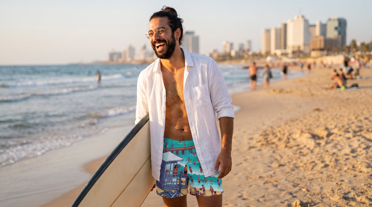 Man in TLV Frishman Beach swim trunks with a surfboard - emohtee Israel swimwear