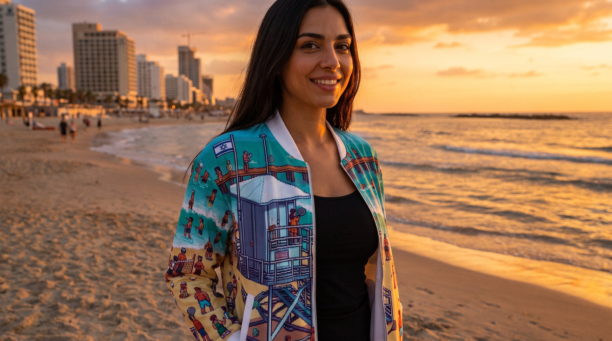 Woman wearing the TLV Frishman Beach 16 Bit bomber jacket at sunset - emohtee Tel Aviv apparel